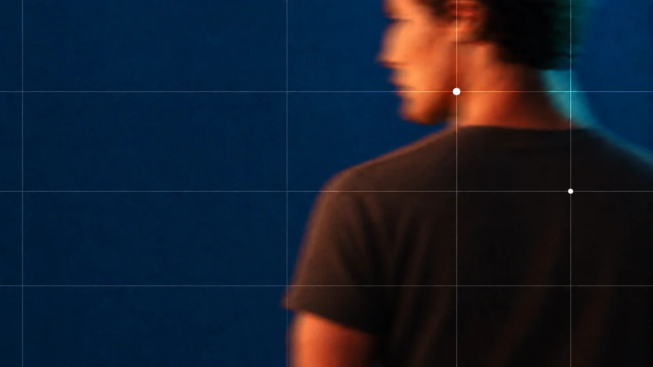 A man seen from behind against a blue grid